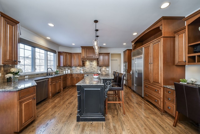 kitchen with open shelves, a center island, appliances with stainless steel finishes, wood finished floors, and a sink