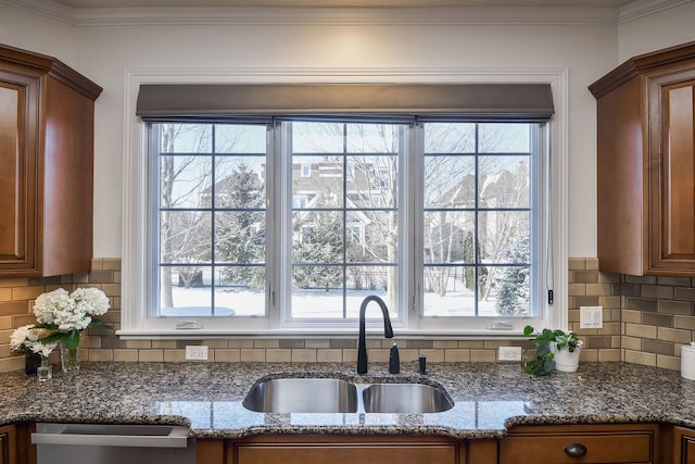 kitchen featuring stainless steel dishwasher, crown molding, a healthy amount of sunlight, and a sink