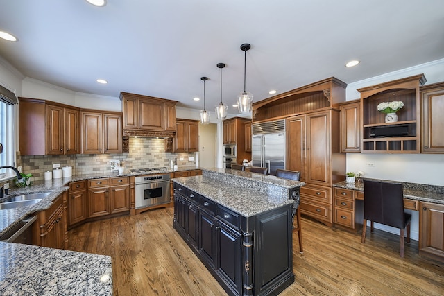 kitchen with a sink, open shelves, wood finished floors, built in desk, and built in appliances