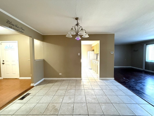 spare room with crown molding, light hardwood / wood-style flooring, a textured ceiling, and a notable chandelier