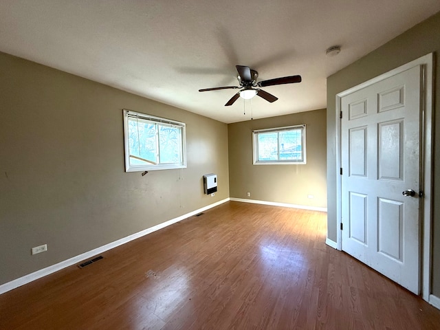 unfurnished bedroom featuring hardwood / wood-style flooring, ceiling fan, and heating unit