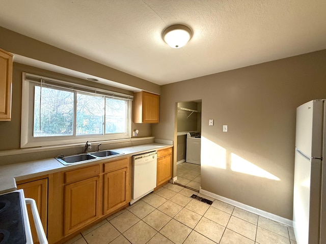 kitchen with washer / clothes dryer, sink, light tile patterned flooring, and white appliances