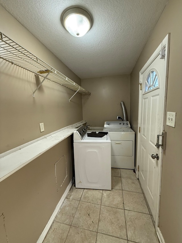 laundry area with light tile patterned floors, a textured ceiling, and washing machine and clothes dryer