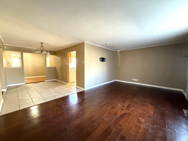 unfurnished room featuring crown molding, light hardwood / wood-style floors, a textured ceiling, and an inviting chandelier