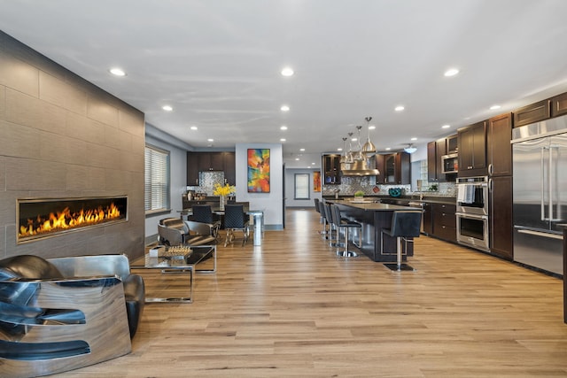 living room with a tile fireplace and light hardwood / wood-style floors