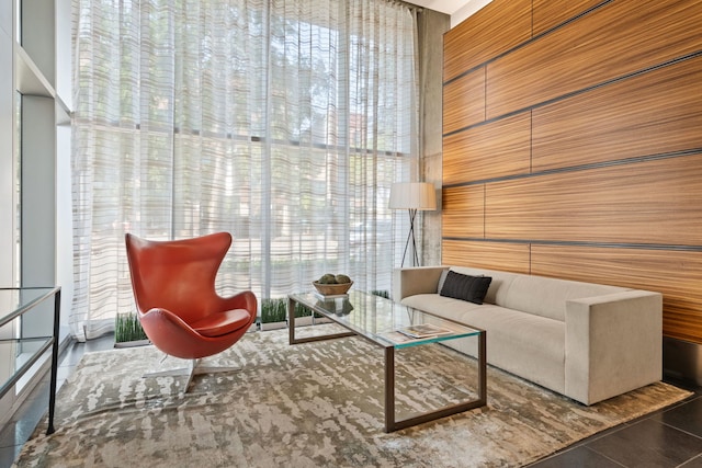 living area featuring a high ceiling, wooden walls, and a healthy amount of sunlight