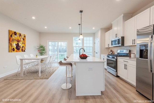 kitchen with appliances with stainless steel finishes, an island with sink, and white cabinets