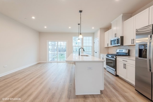 kitchen featuring stainless steel appliances, white cabinets, and a kitchen island with sink