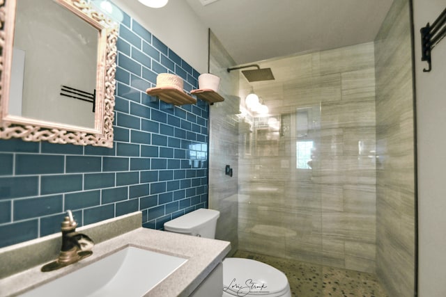 bathroom with tile walls, tiled shower, vanity, decorative backsplash, and toilet