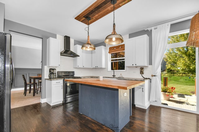 kitchen with stainless steel appliances, wall chimney range hood, white cabinetry, and wood counters