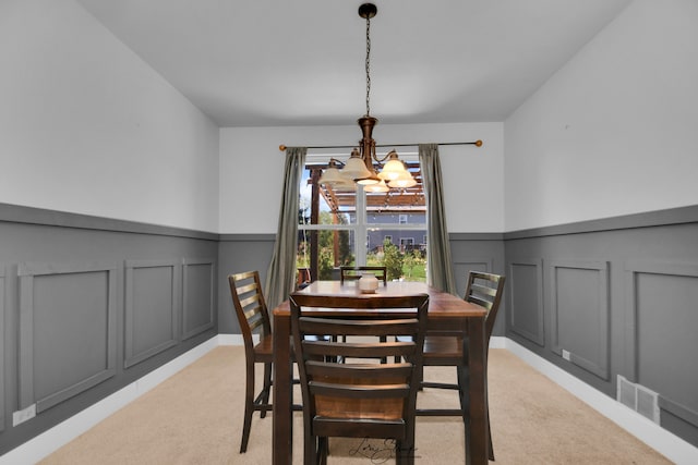 dining area with a chandelier and light colored carpet