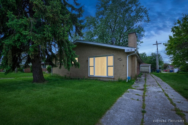 view of side of home featuring a lawn, a garage, and an outbuilding