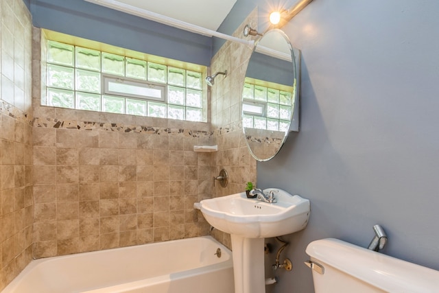 bathroom featuring toilet and tiled shower / bath