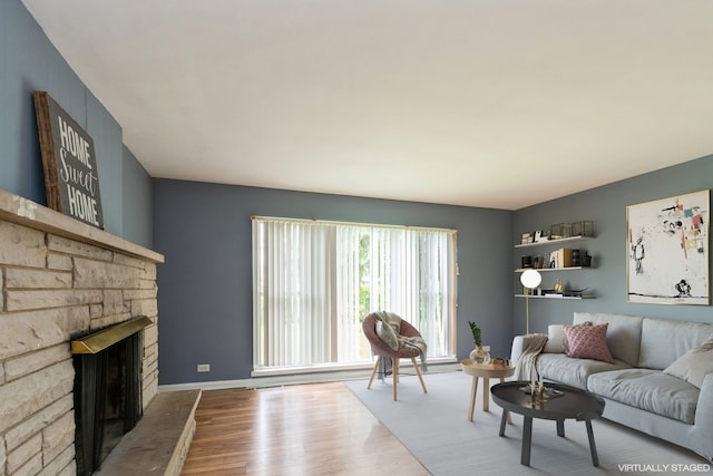 living room with hardwood / wood-style flooring and a stone fireplace