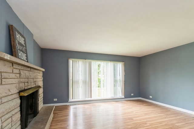 unfurnished living room featuring a stone fireplace and light hardwood / wood-style flooring