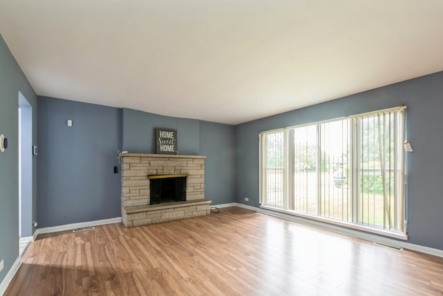 unfurnished living room with a stone fireplace and light hardwood / wood-style flooring