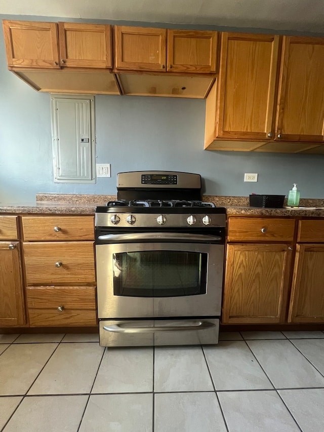 kitchen featuring electric panel, stone countertops, stainless steel range with gas cooktop, and light tile patterned floors