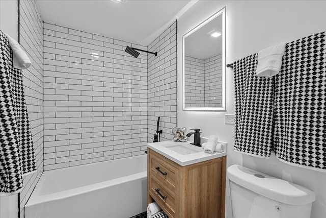 full bathroom featuring tiled shower / bath, vanity, and toilet