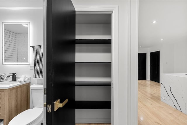 bathroom with hardwood / wood-style flooring, vanity, and toilet