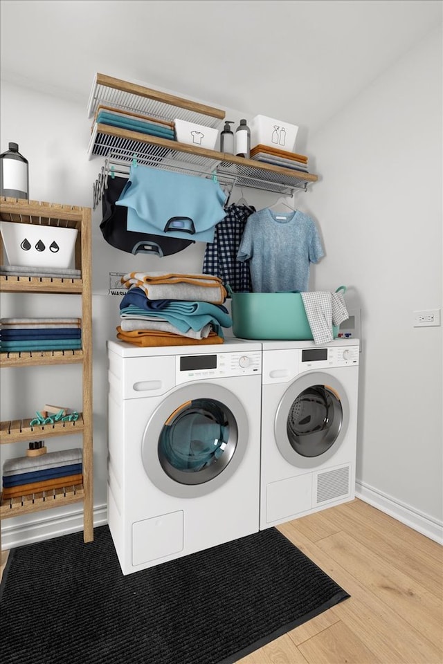 laundry area with light hardwood / wood-style flooring and washer and clothes dryer