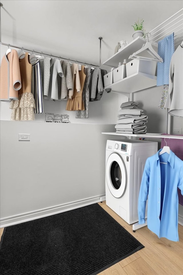 clothes washing area with washer / clothes dryer and light hardwood / wood-style floors