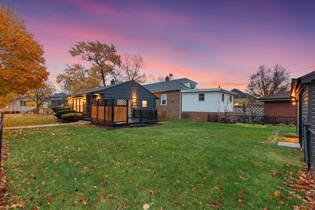 back house at dusk with a lawn and a wooden deck