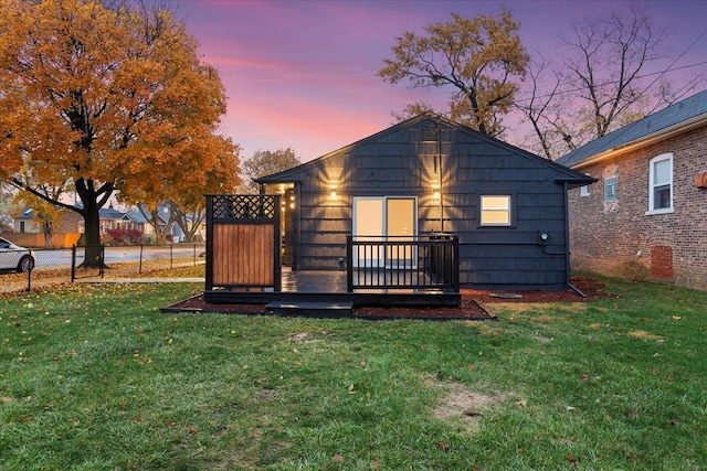 back house at dusk with a yard and a deck