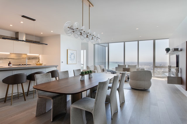 dining room with expansive windows, light hardwood / wood-style flooring, a water view, and an inviting chandelier