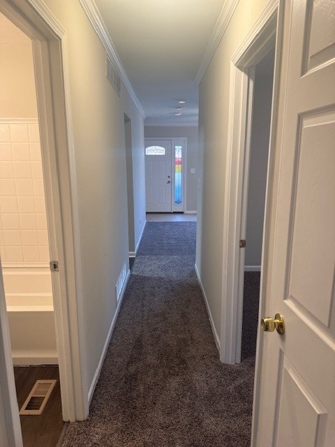 hallway featuring dark colored carpet and crown molding