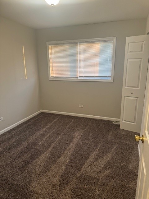 spare room with dark carpet