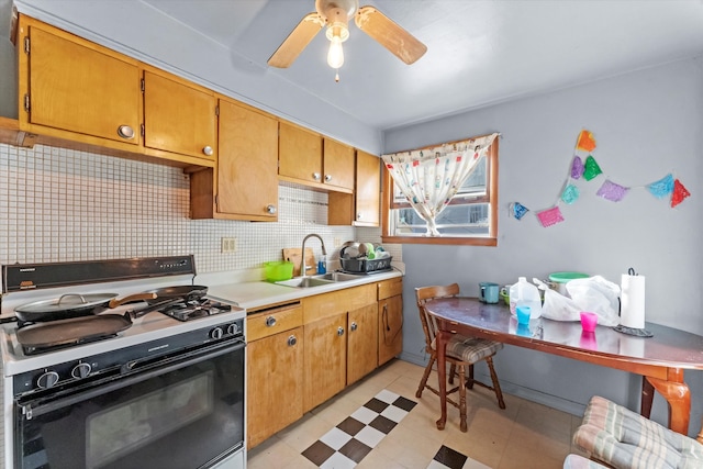 kitchen featuring gas stove, backsplash, sink, and ceiling fan