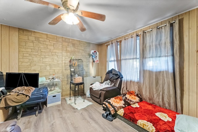 bedroom featuring hardwood / wood-style flooring, ceiling fan, and wooden walls