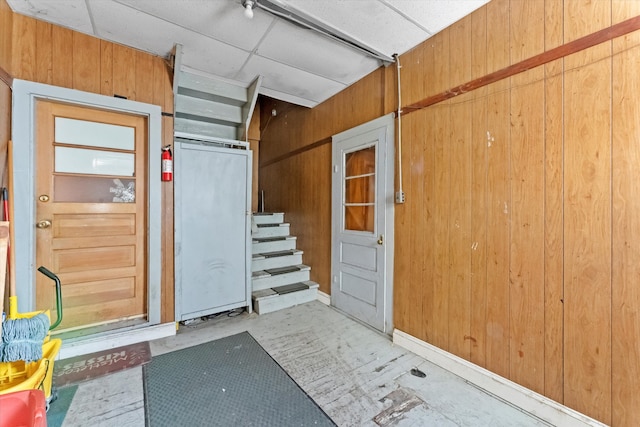 interior space with a drop ceiling and wood walls