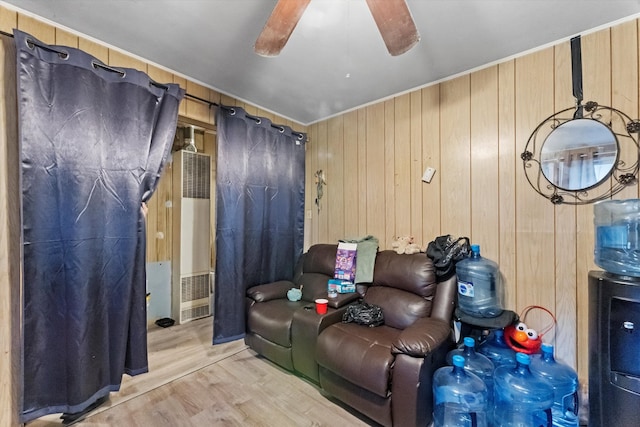 home theater room with light wood-type flooring, wooden walls, and ceiling fan