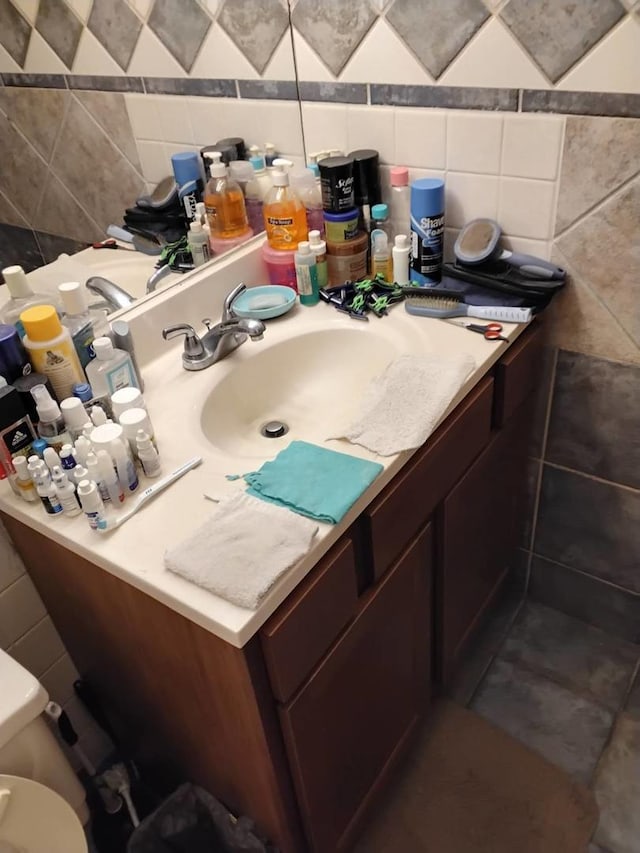 bathroom with vanity, toilet, and tile walls