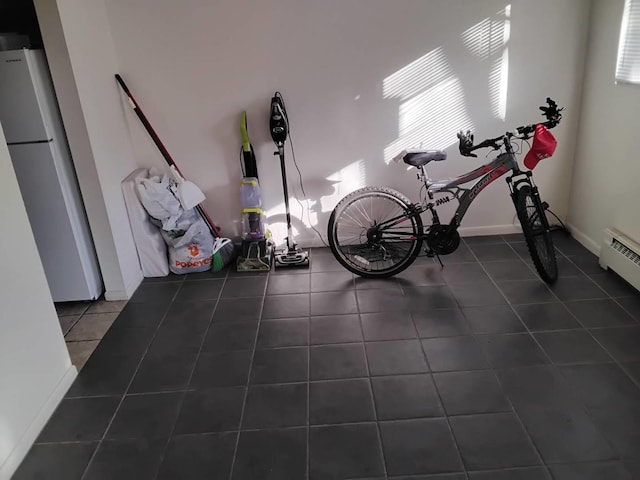 workout room with dark tile patterned floors and a baseboard radiator