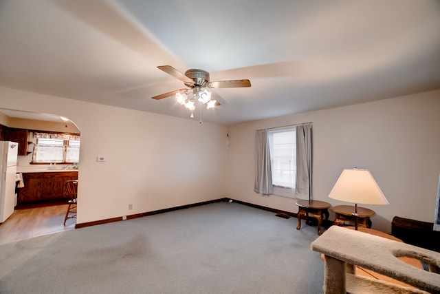 sitting room featuring ceiling fan, a healthy amount of sunlight, and light colored carpet