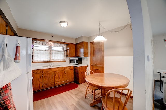 kitchen featuring pendant lighting, light hardwood / wood-style floors, white refrigerator with ice dispenser, and sink