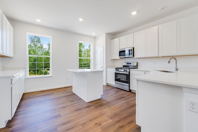 kitchen featuring stainless steel appliances, hardwood / wood-style flooring, white cabinetry, and a center island