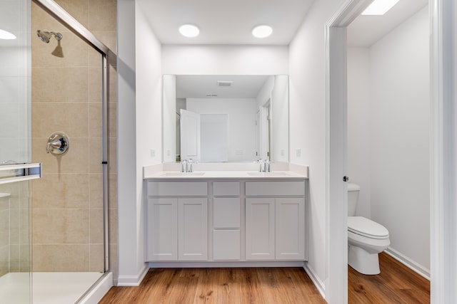 bathroom featuring hardwood / wood-style flooring, a shower with shower door, vanity, and toilet