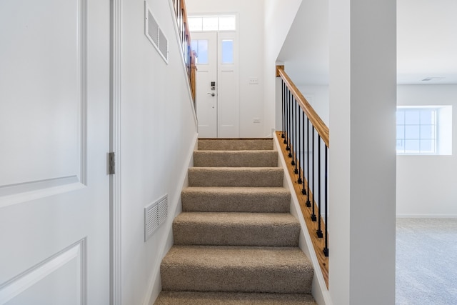 staircase with a healthy amount of sunlight and carpet floors