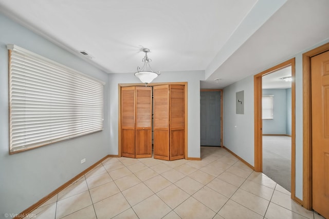 unfurnished bedroom with light tile patterned floors, multiple windows, electric panel, and a closet