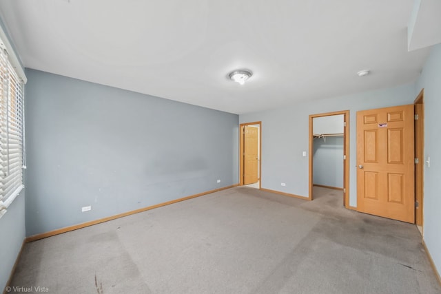 unfurnished bedroom featuring a walk in closet, light carpet, and a closet