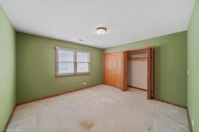 unfurnished bedroom featuring light colored carpet and multiple closets