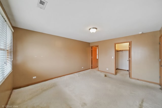 unfurnished bedroom featuring a spacious closet, light carpet, and a closet