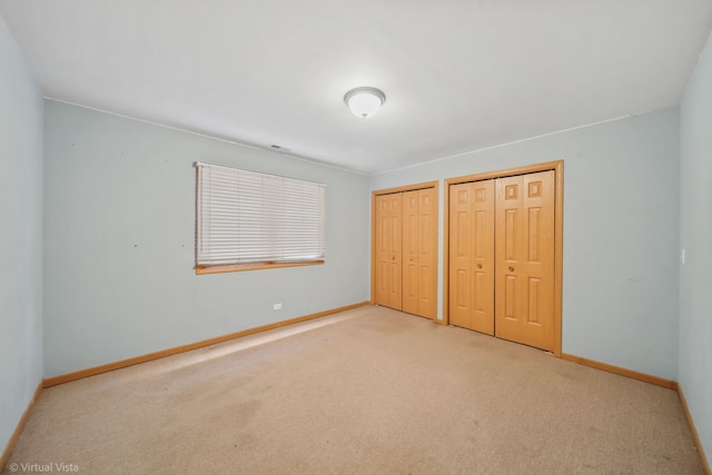 unfurnished bedroom with carpet floors and two closets