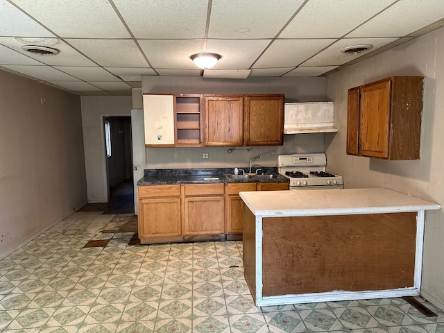 kitchen with a paneled ceiling, sink, white range with gas stovetop, and extractor fan