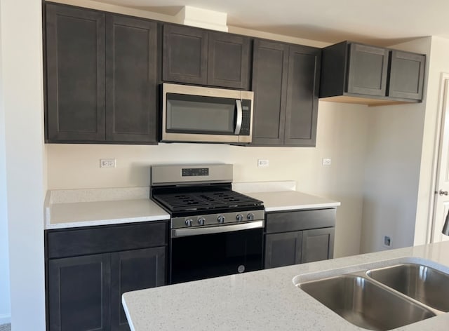 kitchen with stainless steel appliances, sink, and light stone counters