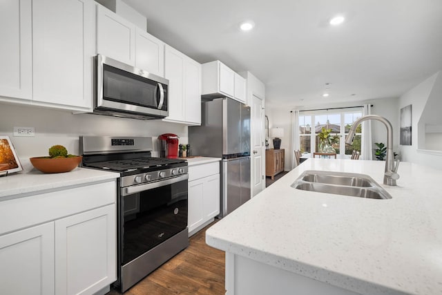 kitchen featuring light stone counters, appliances with stainless steel finishes, dark hardwood / wood-style flooring, sink, and white cabinets