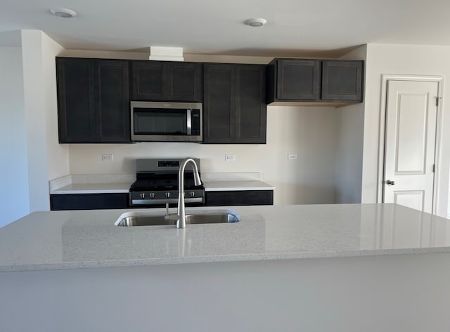 kitchen featuring a kitchen island with sink, appliances with stainless steel finishes, and light stone counters